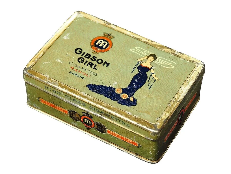 The_'Gibson_Girl_Cigarettes_Manoli_Berlin'_is_a_vintage_tin_box_featuring_an_illustration_of_the_iconic_Gibson_Girl._Thi